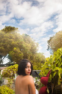 Portrait of beautiful young woman against trees