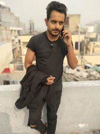 Young man using mobile phone standing in city