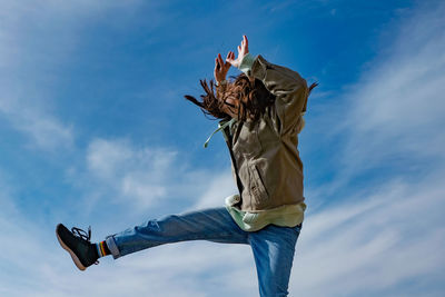 Low angle view of person jumping against sky