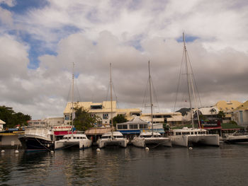 Boats moored at harbor against sky