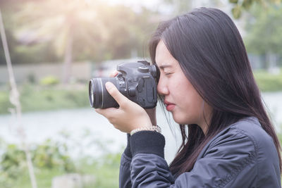 Woman photographing against lake