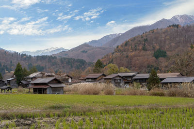 Houses on field by mountains against sky