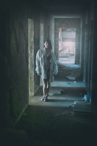 Young fashion model standing in corridor of abandoned building