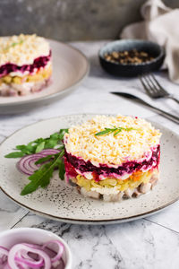 Herring under a fur coat traditional new year's salad of vegetables and fish on a plate on the table