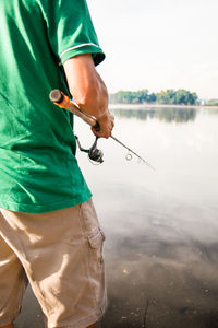 Midsection of man fishing in lake