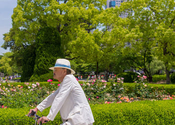 Side view of man standing by flowering plants