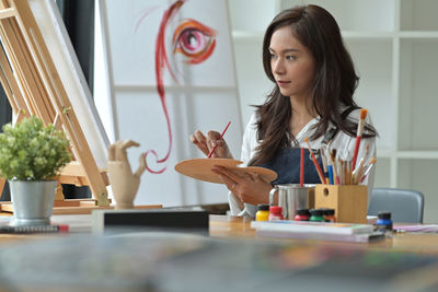 Portrait of young woman sitting on table at home