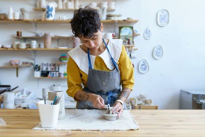 Creative process in pottery studio. young artist girl modeling sculpture from raw clay for potter