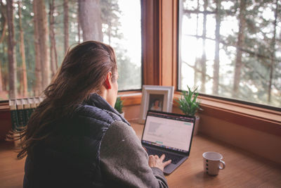 Woman using phone while sitting on table at home