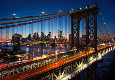 Bridge over river against sky in city during sunset