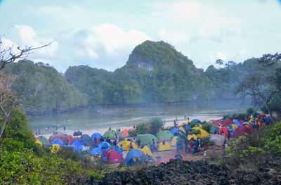 Group of people on mountain by river against sky