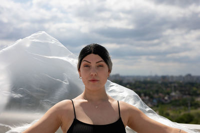 Portrait of young woman against sky