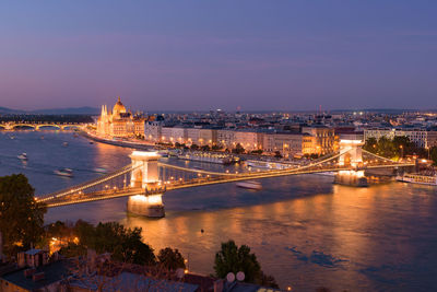 Illuminated bridge over river against sky in city at night