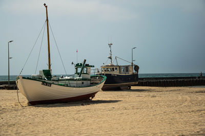 Ship moored on beach against sky