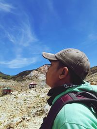 Close-up of man wearing hat looking away while standing against sky