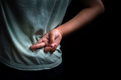 Close-up of man holding hands over black background