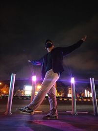 Man standing at illuminated city against sky at night