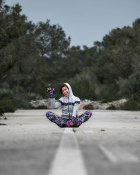 Woman sitting on swing against trees