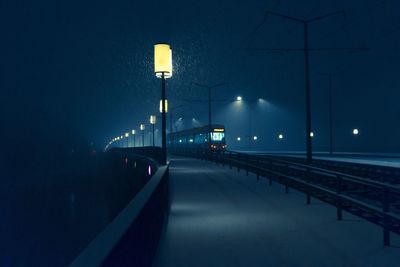 Cable car on railway bridge during snowfall at night