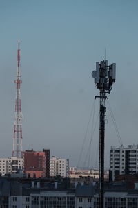 Low angle view of cranes against buildings in city against sky