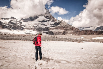 Woman standing on snowcapped mountain against sky