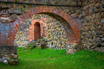 Archway of historic building by grassy field