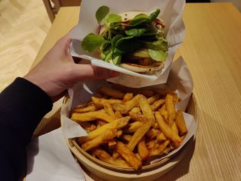 Cropped hand of person having burger and fries 