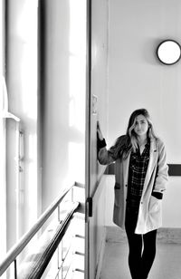 Portrait of young woman standing by wall