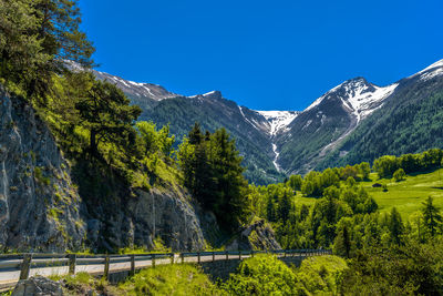 Scenic view of trees and mountains against clear blue sky