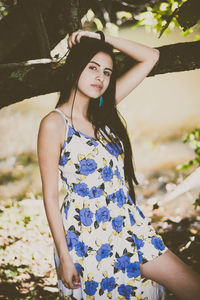 Portrait of young woman standing against tree