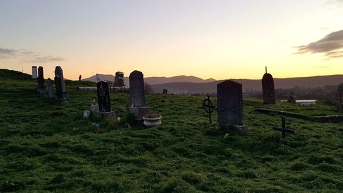 Cross on cemetery against sky during sunset