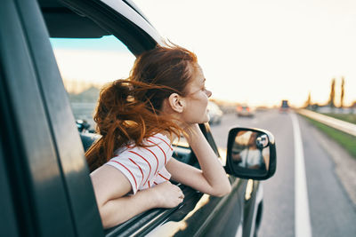 Side view of girl with car on window