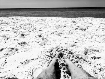 Low section of woman on beach against sky