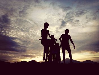 Silhouette of people against cloudy sky