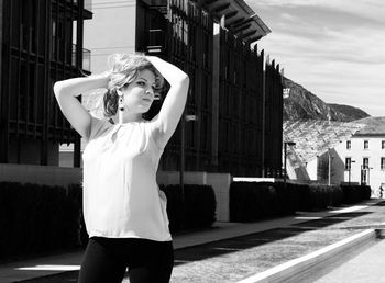 Portrait of young woman standing against built structure