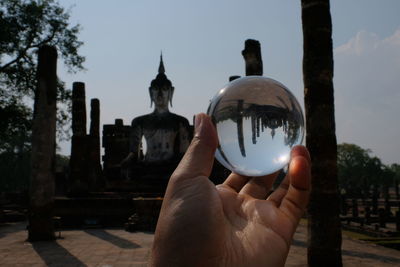 Midsection of person holding crystal ball against temple