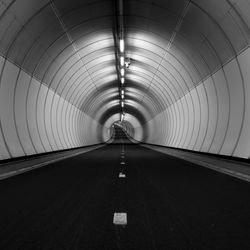 Illuminated empty road in tunnel