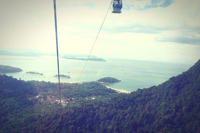 Overhead cable car over sea against sky