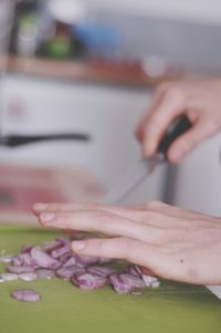 Cropped hands of woman chopping onions on cutting board at home