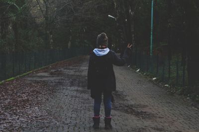 Rear view of woman standing on footpath in forest