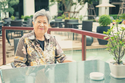 Elder woman resting relaxing on balcony terrace at hotel resort. elderly senior leisure lifestyle