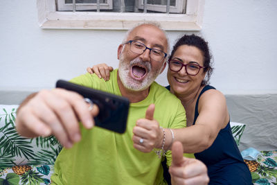 Portrait of happy man photographing woman using mobile phone