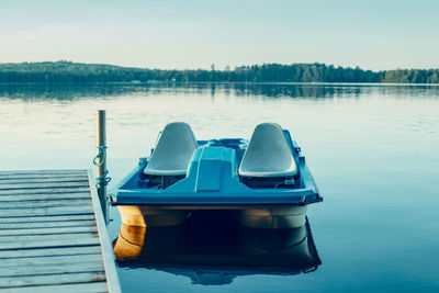 Old blue pedal boat tied to wooden dock pier at canadian ontario lake in muskoka. travel canadian 