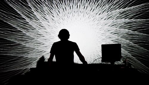 Silhouette man in front of illuminated projection light during performance