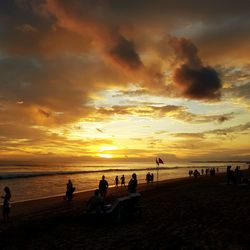 Silhouette people on beach against sky during sunset