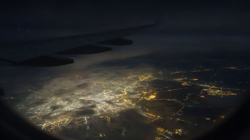 Aerial view of illuminated cityscape seen through airplane window