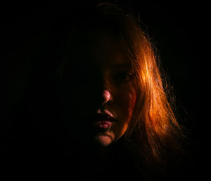 Close-up portrait of teenage girl in darkroom