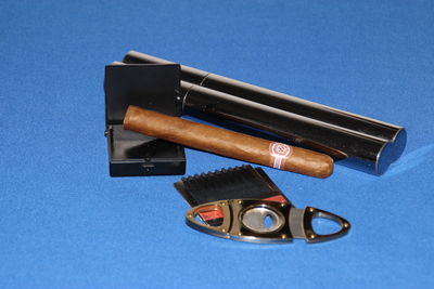 Close-up of cigar and cutter with boxes on blue surface