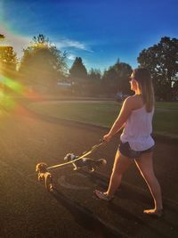 Young woman walking with dogs on footpath in park