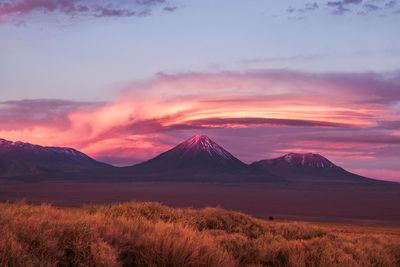 Scenic view of lake and mountains against cloudy sky during sunset